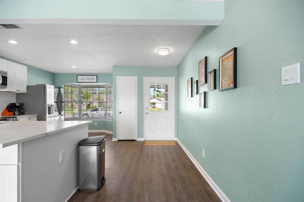 Irving, TX 75060 Wood-finish flooring, recessed lighting, bay window, white paneled door, and white trim