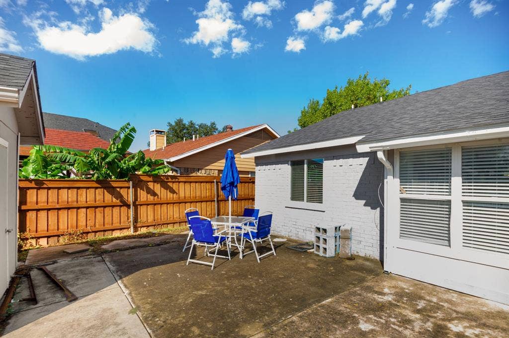 Irving, TX 75060 Private fenced yard with concrete patio, painted brick exterior, and dark shingle roofing