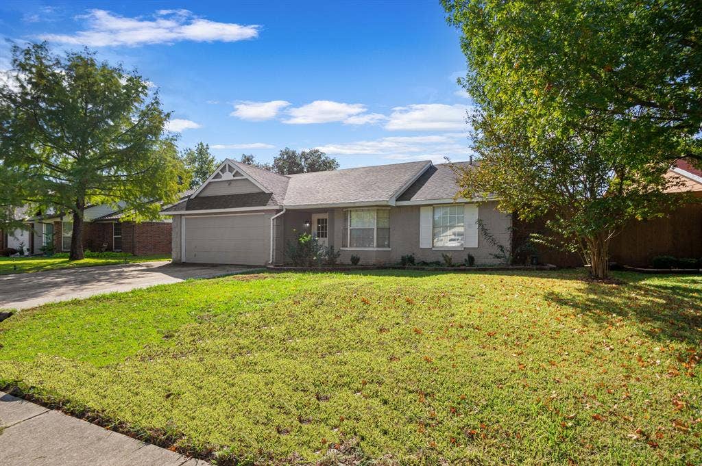 Irving, TX 75060 Single-story residence featuring a two-car garage, pitched roof, and mature trees