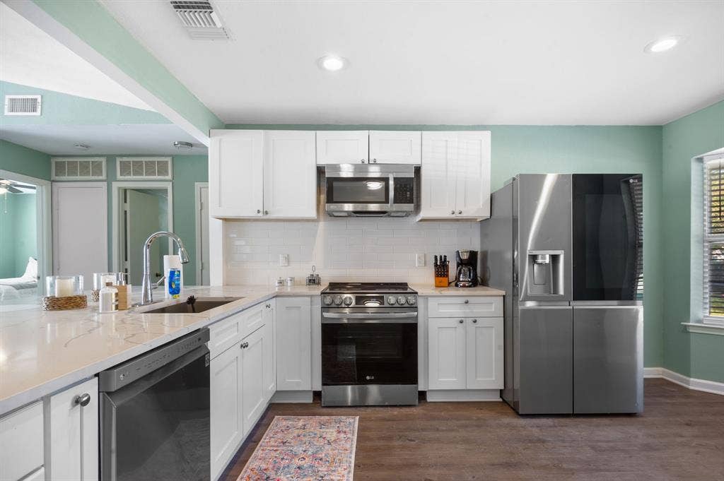 Irving, TX 75060 White shaker cabinetry with stainless steel appliances, white quartz countertops, and a subway tile backsplash