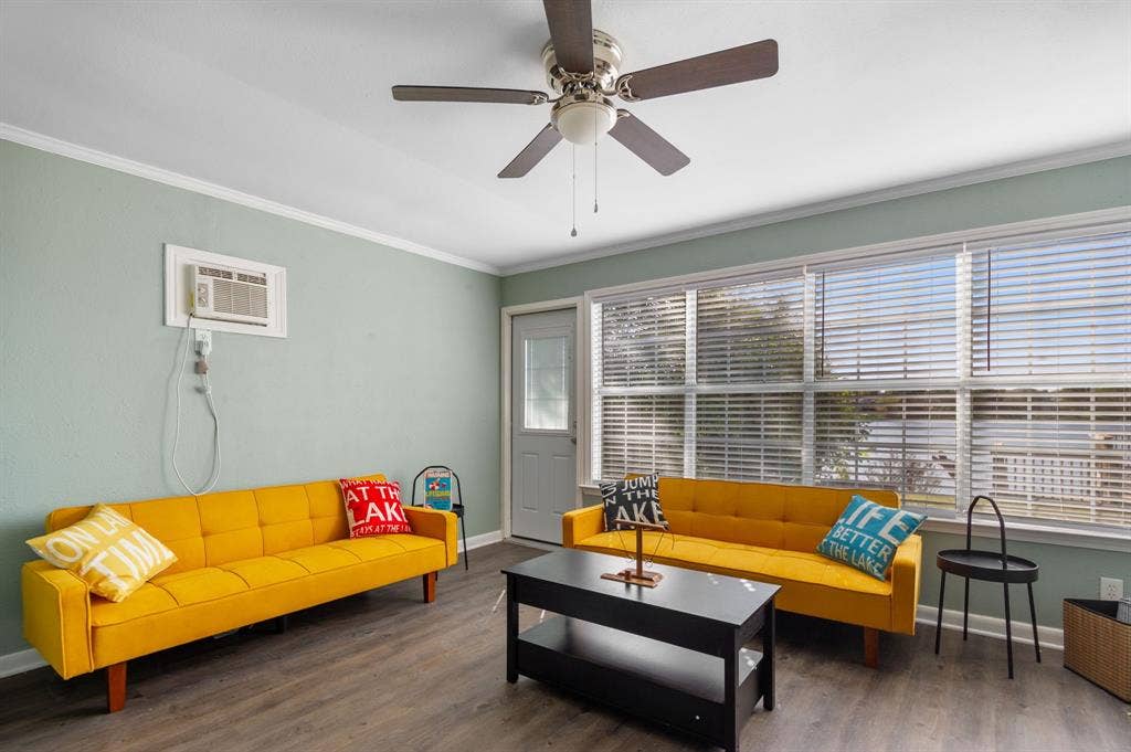 Irving, TX 75060 Wood-finish flooring, ceiling fan, multiple windows with blinds, and a white entry door with glass paneling