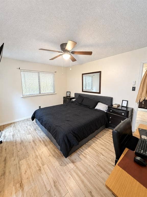 Wood-finish flooring, ceiling fan with integrated lighting, window with blinds, wall-mounted mirror, and a built-in wall niche