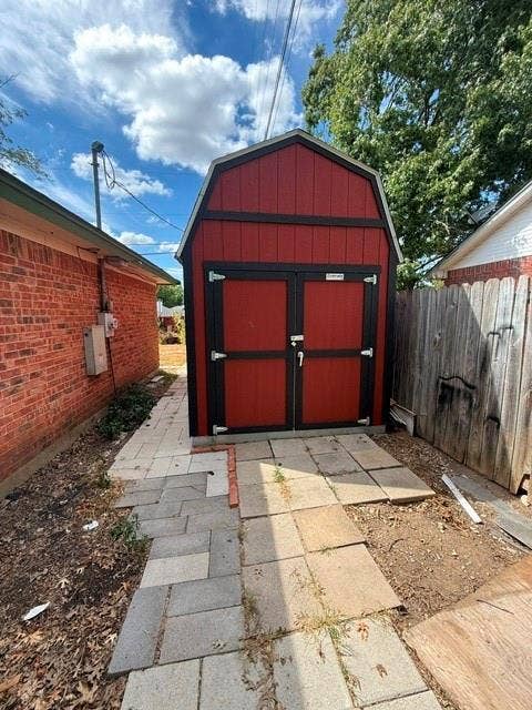 Barn-style storage shed with double doors and black trim