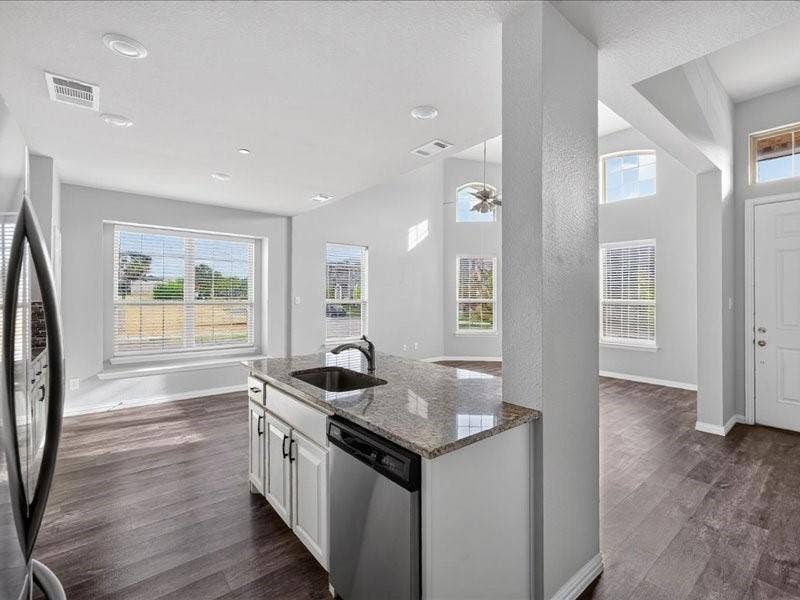 Kitchen island featuring a granite countertop, undermount sink, and stainless steel dishwasher