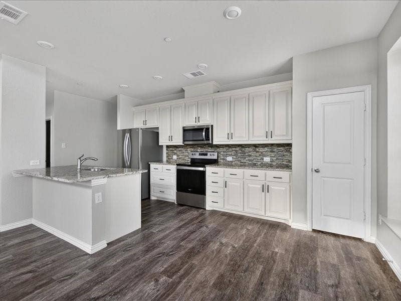 White cabinetry with dark hardware, stainless steel appliances, mosaic tile backsplash, and wood-finish flooring
