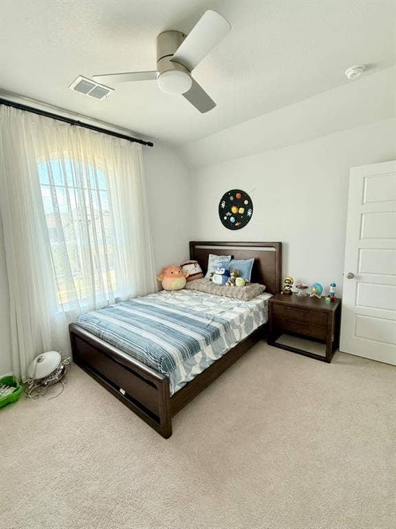 Ceiling fan with integrated lighting, arched window with white sheer drapery, light neutral carpeting, white interior door, and a built-in smoke detector