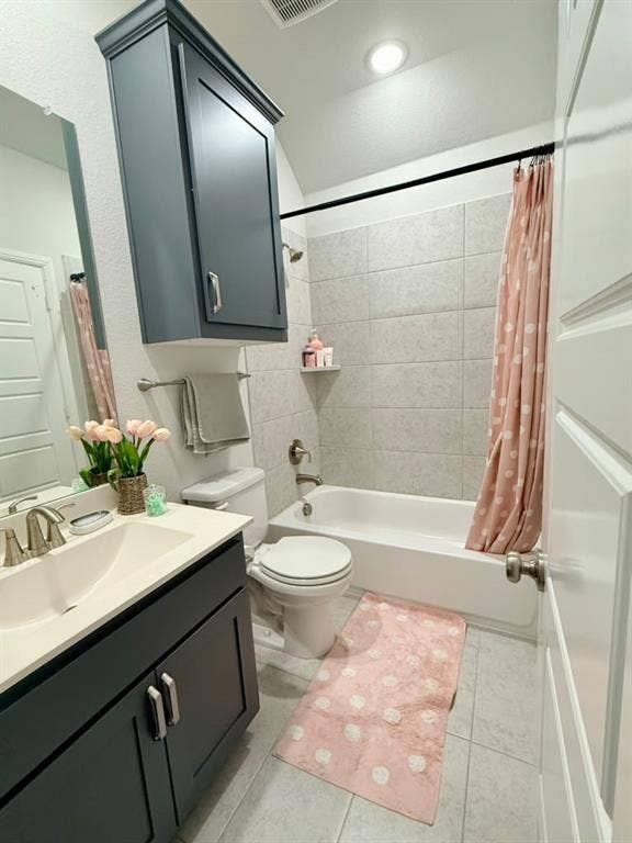 Bathroom with gray tile flooring, a white bathtub, and a dark vanity with a white countertop