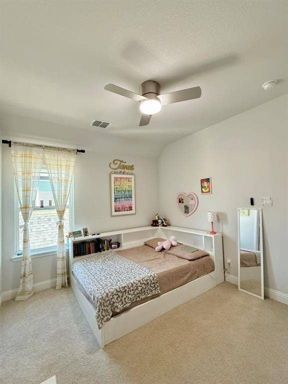Neutral-toned carpet flooring, a ceiling fan with integrated lighting, and a corner built-in shelving unit