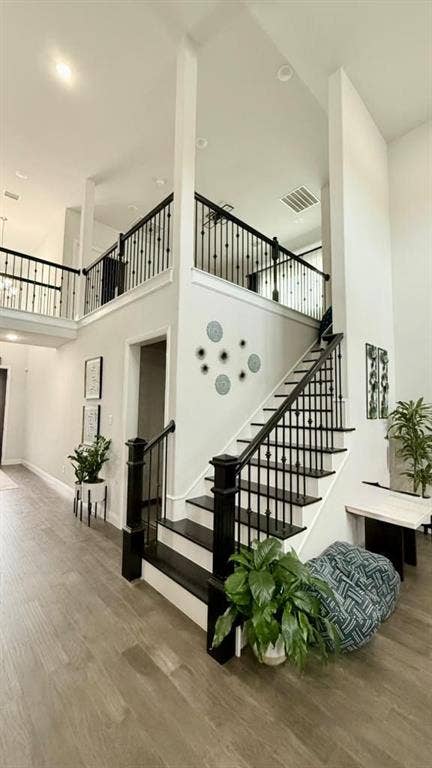 Two-story foyer featuring a staircase with black painted handrails and spindles, wood-finish flooring, and recessed ceiling lighting