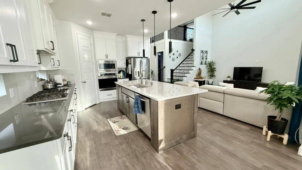 Kitchen with white cabinetry, gray countertops, and a central island with a sink