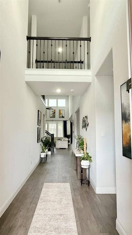 Two-story foyer with wood-finish flooring, recessed lighting, and a second-level balcony with black wrought iron railing