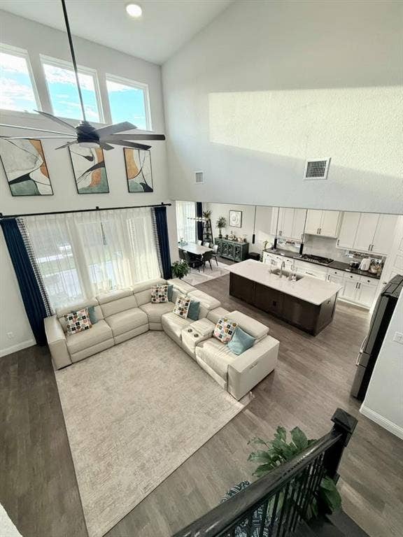 Vaulted ceilings, wood-finish flooring, recessed lighting, island kitchen with white cabinetry, and large windows