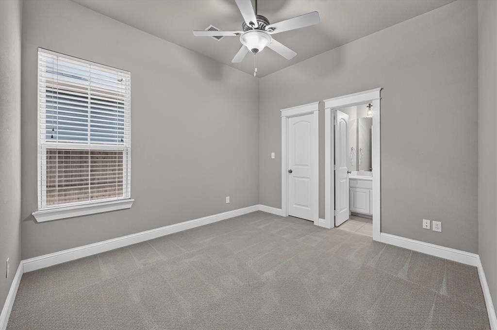 Carpeted room featuring a ceiling fan with integrated lighting, a window with blinds, and white trim