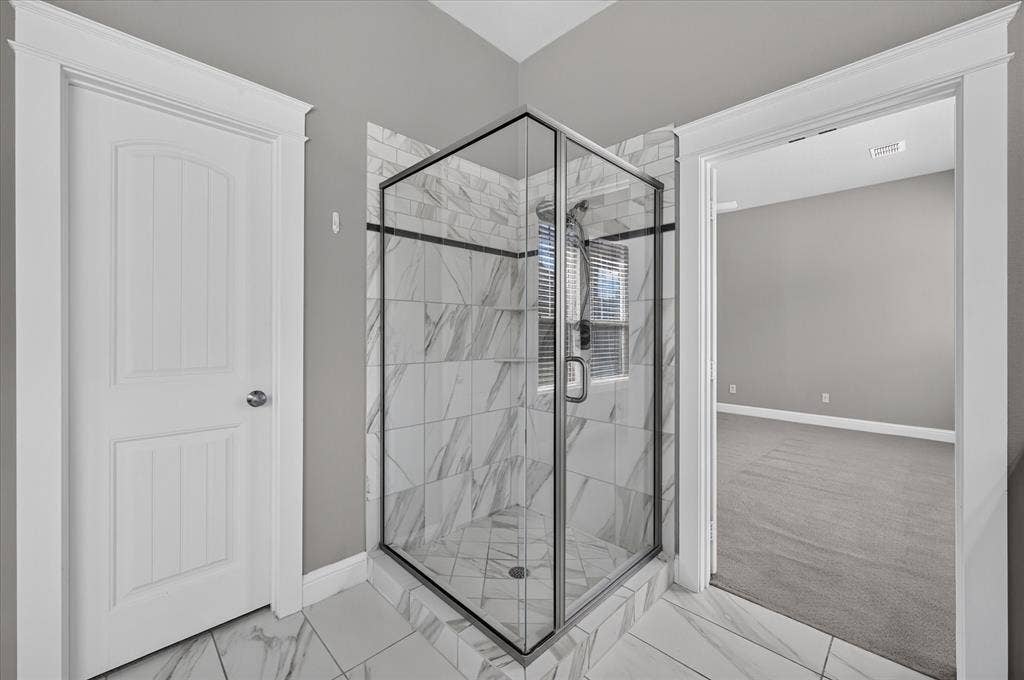 Corner glass-enclosed shower with a tiled surround, a built-in shower niche, and a window
