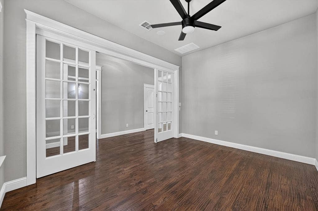 Wood-finish flooring, white French doors, ceiling fan, and light gray wall finish