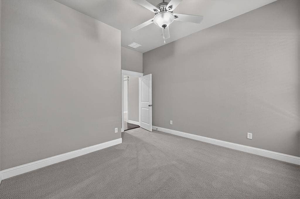 Neutral tone walls, plush carpeting, ceiling fan with integrated lighting, and white trim