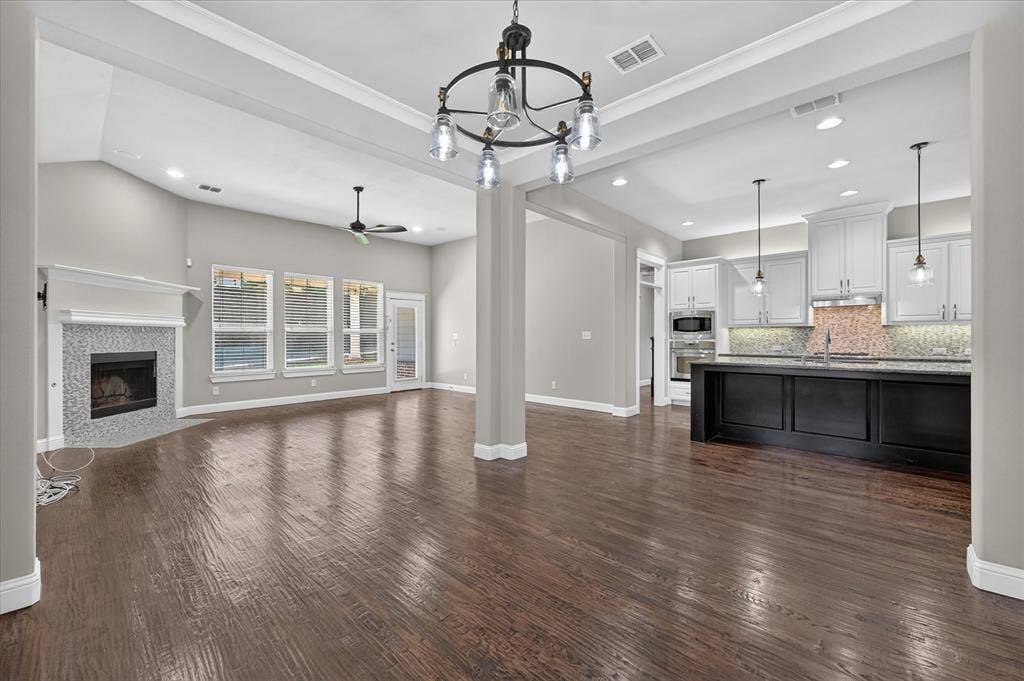 Expansive living space featuring wood-finish flooring, a fireplace with tile surround, and vaulted ceilings