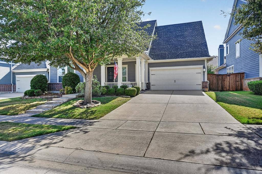Charming single-story home featuring a two-car garage, manicured front landscaping with mature trees, and a concrete driveway