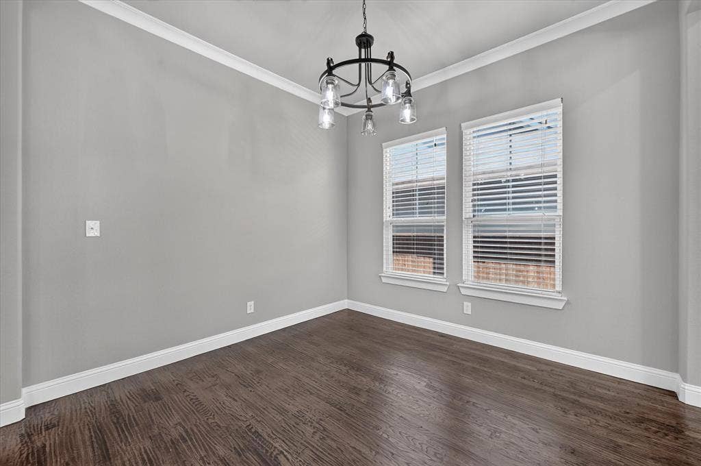Wood-finish flooring, crown molding, and a contemporary chandelier