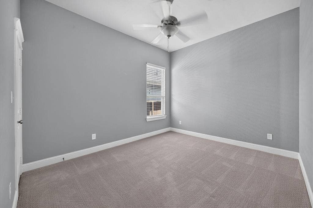 Carpeted room featuring a ceiling fan, window with blinds, and light gray walls