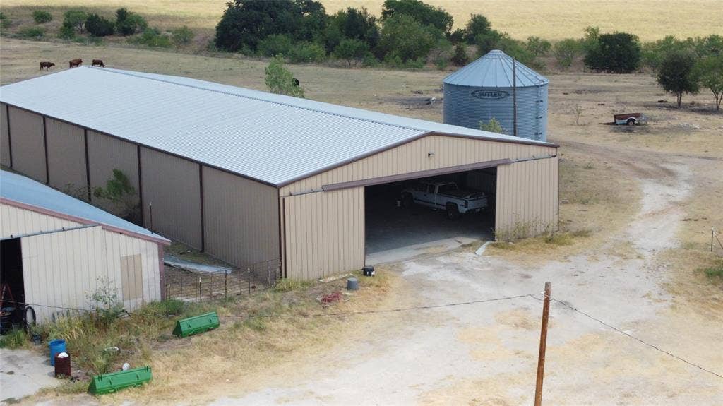 Metal-sided barn structure with a light-colored roof, featuring a large open bay