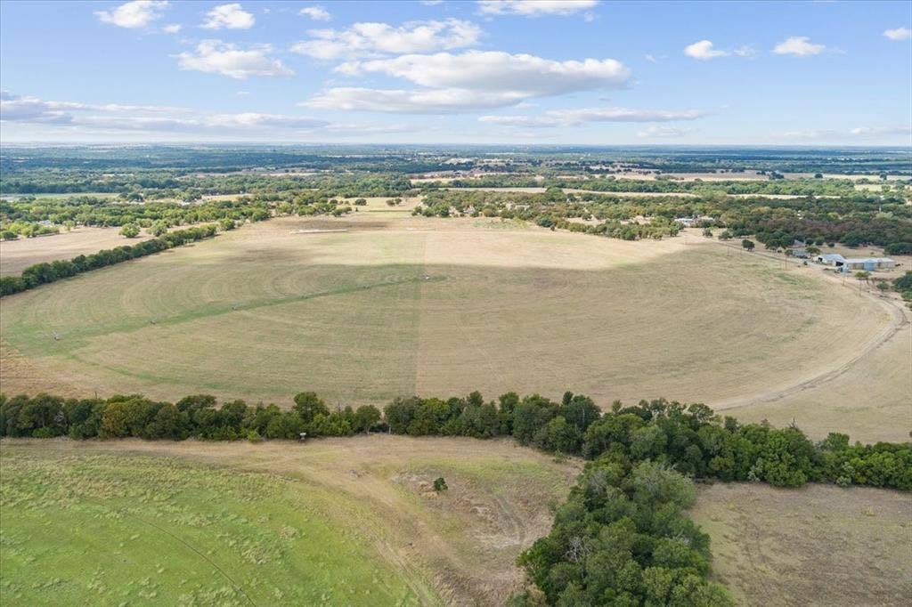 Expansive land parcel featuring open fields and mature tree lines
