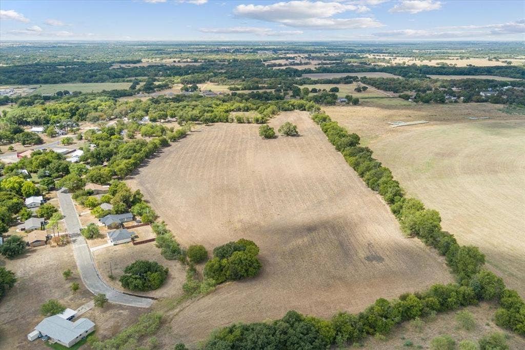 Expansive land parcel with surrounding mature trees and clear, buildable terrain
