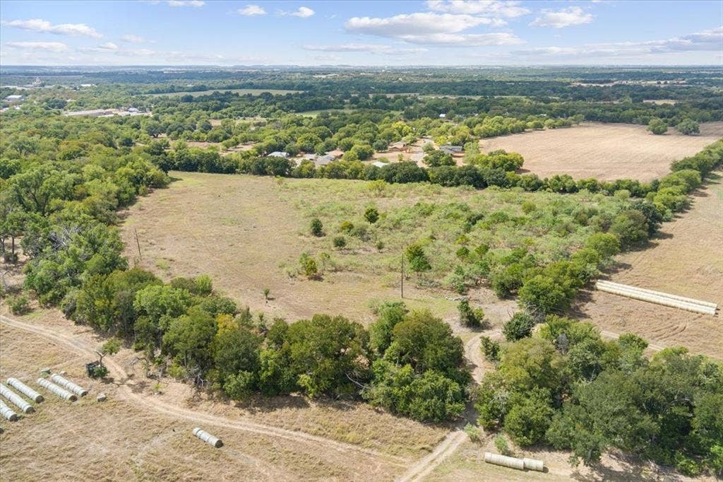 Expansive land parcel featuring open fields and mature tree lines