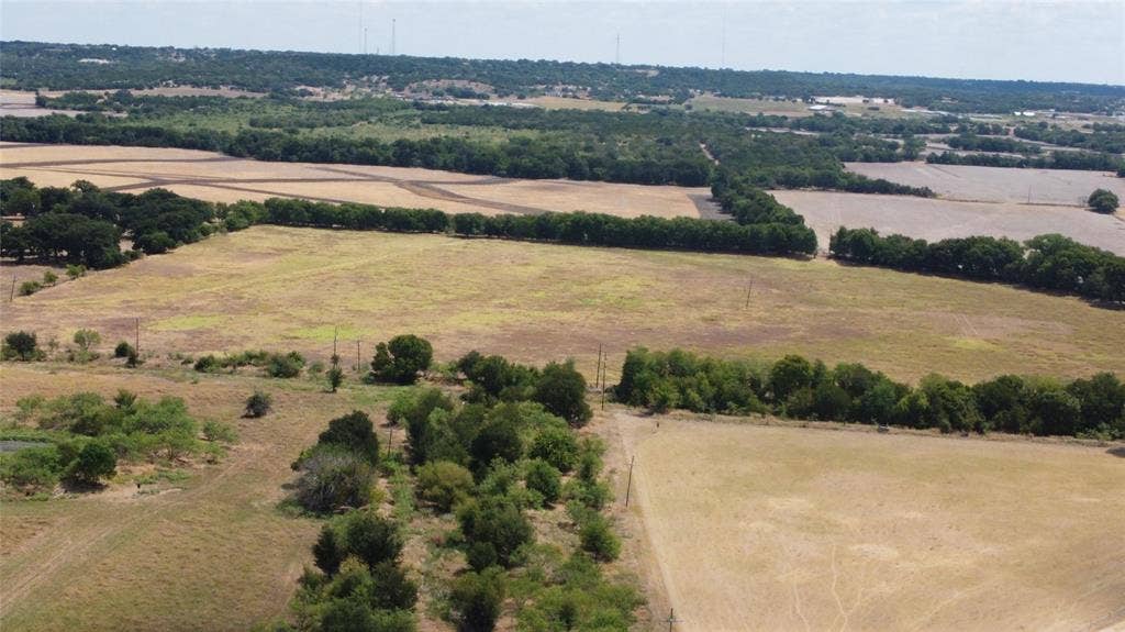 Expansive rural landscape featuring fields and mature tree lines