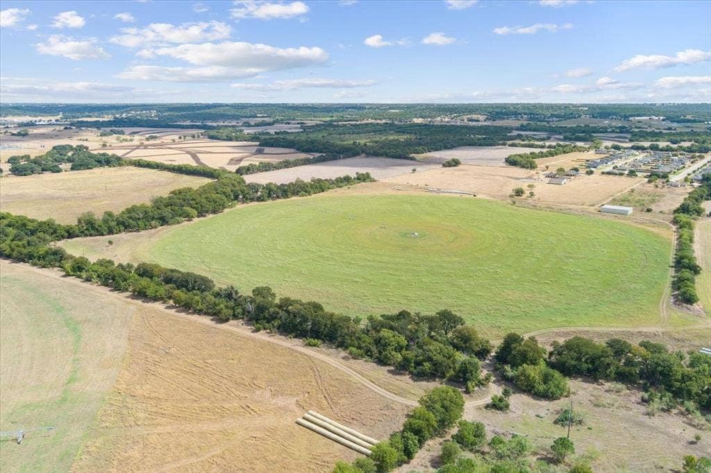 Expansive acreage featuring a circular field, mature tree lines, and surrounding natural terrain