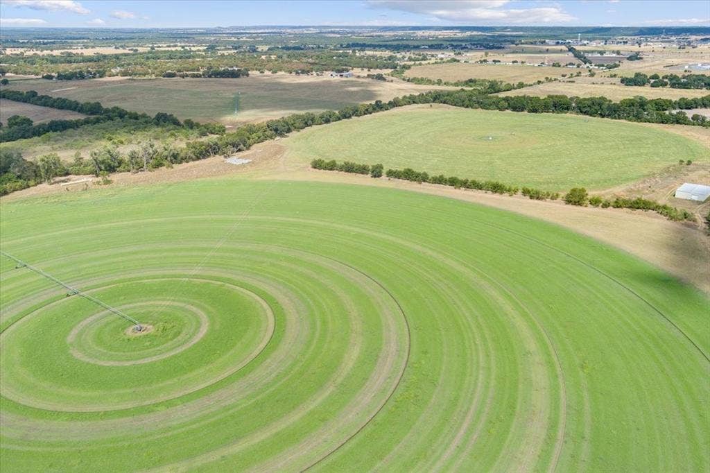 Expansive green fields with circular irrigation patterns, including a visible irrigation system