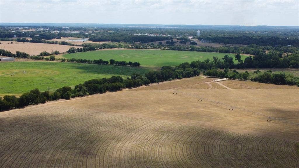 Expansive agricultural land featuring cultivated fields, natural tree lines, and distant open spaces