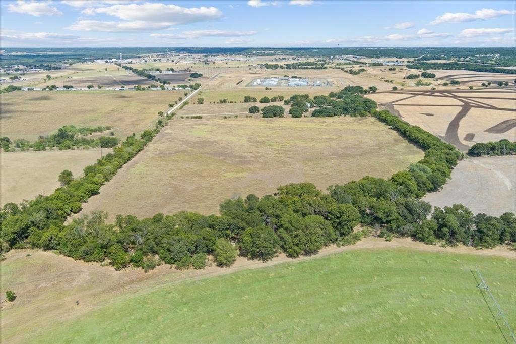Expansive agricultural land featuring a tree-lined perimeter and clear skies