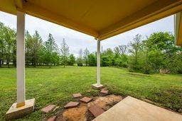 12770 E US 175 E, Larue, TX 75770 Covered concrete patio featuring structural support columns, flagstone accents, and a grass lawn with perimeter trees