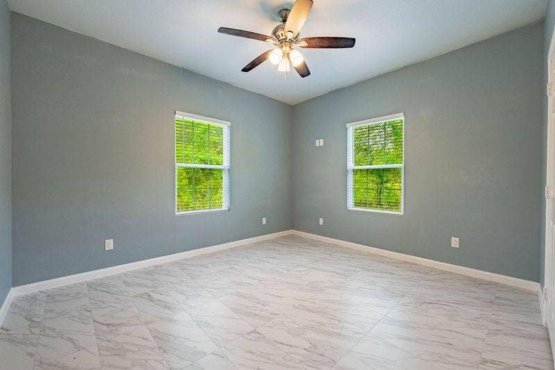 12770 E US 175 E, Larue, TX 75770 Room featuring stone-patterned tile flooring, two windows with horizontal blinds, and a multi-light ceiling fan