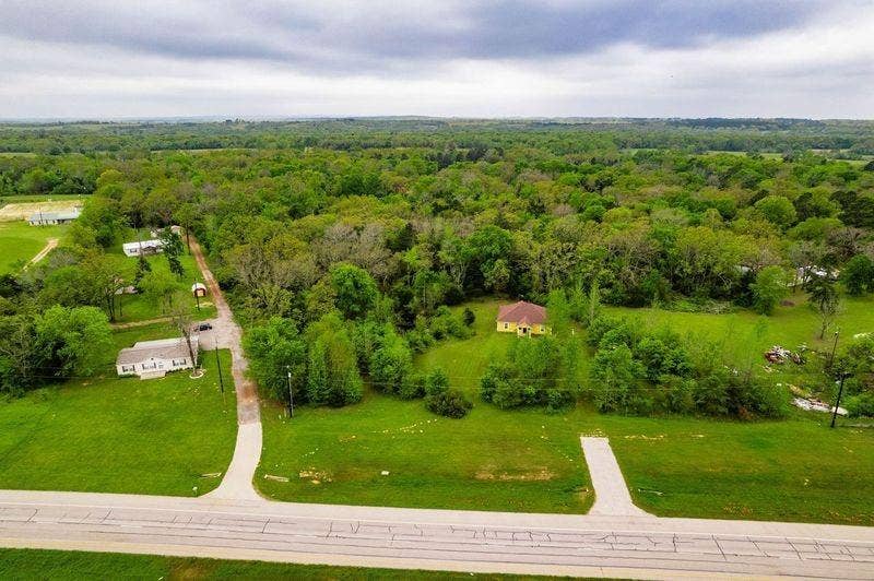12770 E US 175 E, Larue, TX 75770 Aerial perspective of expansive acreage featuring a detached residential structure, mature timber, open grass expanses, and private paved driveway access