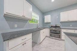 12770 E US 175 E, Larue, TX 75770 Kitchen featuring white cabinetry, dark stone countertops, stainless steel dual-oven range, and light-toned patterned flooring
