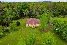 12770 E US 175 E, Larue, TX 75770 Single-story residence featuring a hipped roof, light-toned exterior siding, expansive green grounds, and mature perimeter trees
