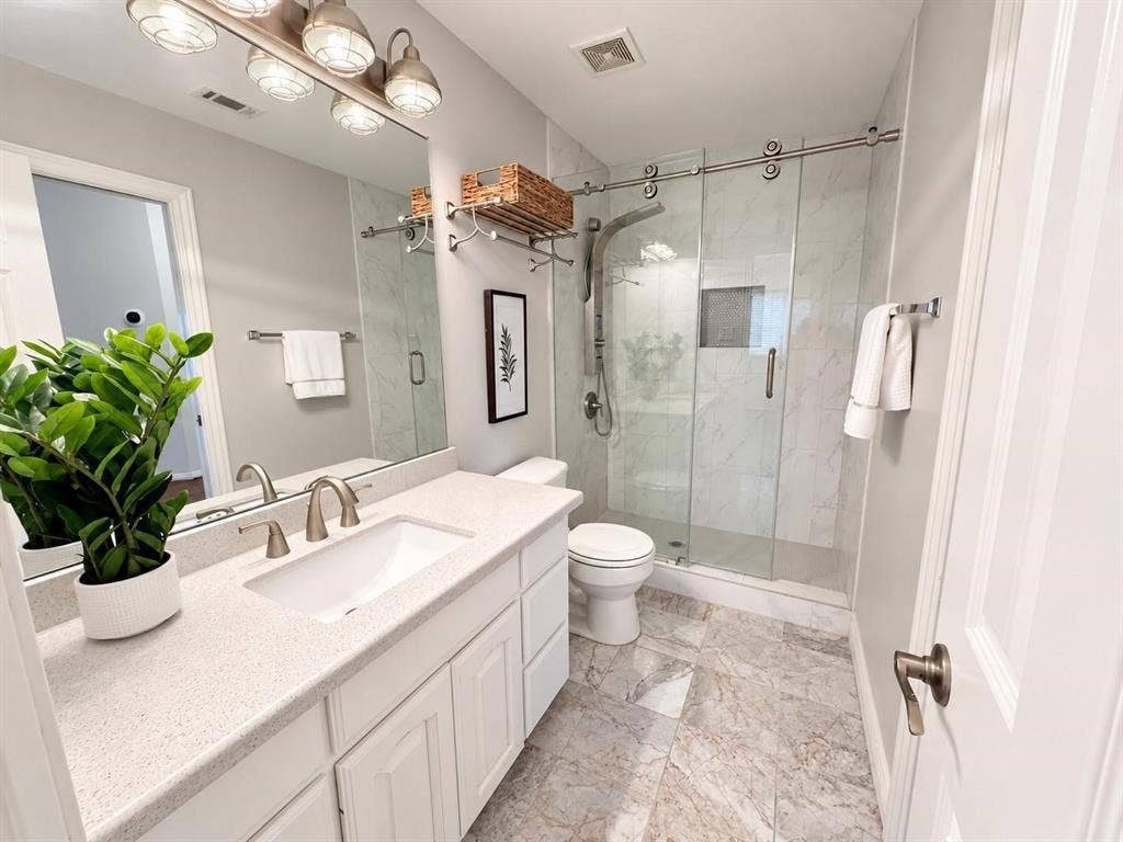 2917 Waterford Drive, Irving, TX 75063 White vanity with a light speckled countertop, undermount sink, and brushed nickel faucet