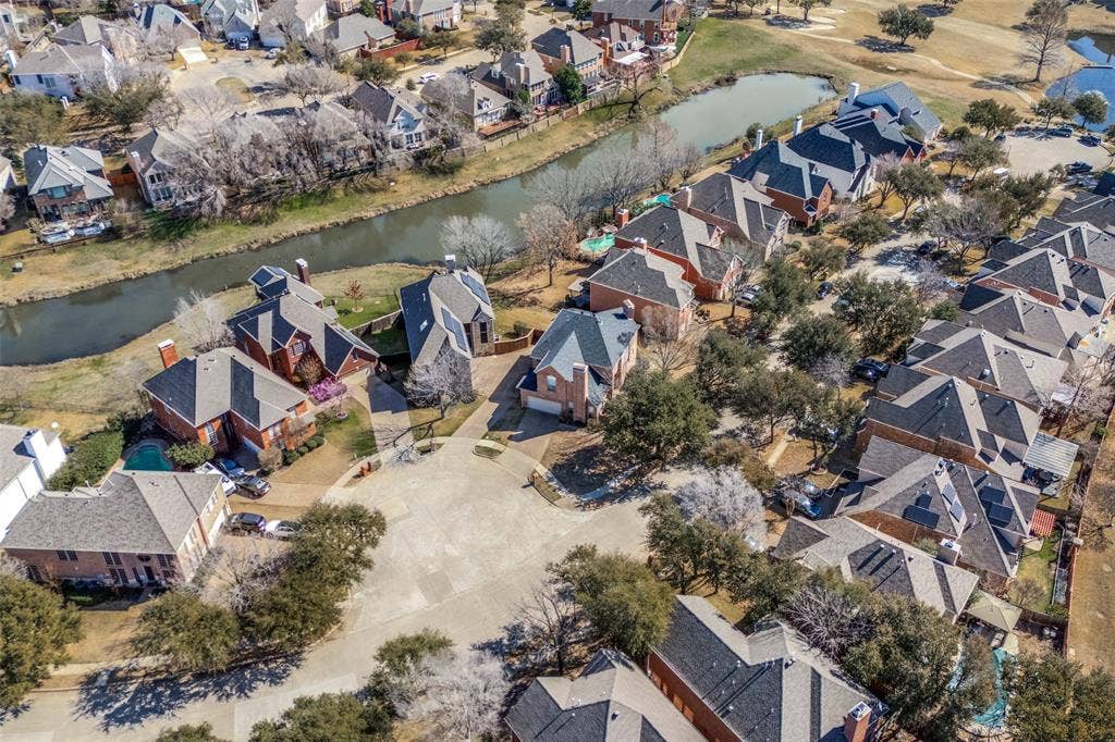 2917 Waterford Drive, Irving, TX 75063 Aerial perspective showcasing a residential community with mature landscaping, multiple properties with red brick exteriors, and a winding waterway