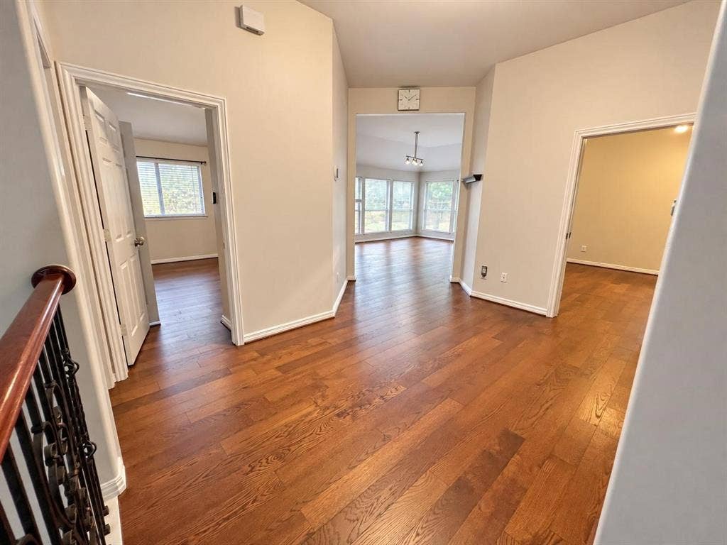 2917 Waterford Drive, Irving, TX 75063 Hardwood flooring throughout, multiple doorways leading to separate rooms, bright windows with natural light, and a wrought iron and wood-finish railing