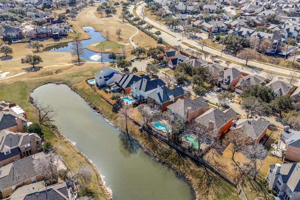 2917 Waterford Drive, Irving, TX 75063 Aerial perspective showcasing a residential community with homes featuring private swimming pools, situated along a waterway, and bordering a golf course with multiple water features