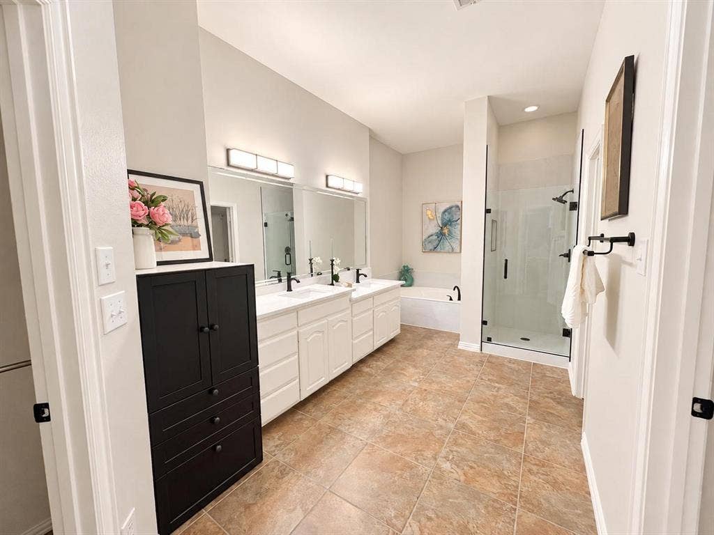 2917 Waterford Drive, Irving, TX 75063 Spa-inspired primary bathroom featuring dual vanities with white cabinetry, black hardware accents, and quartz countertops