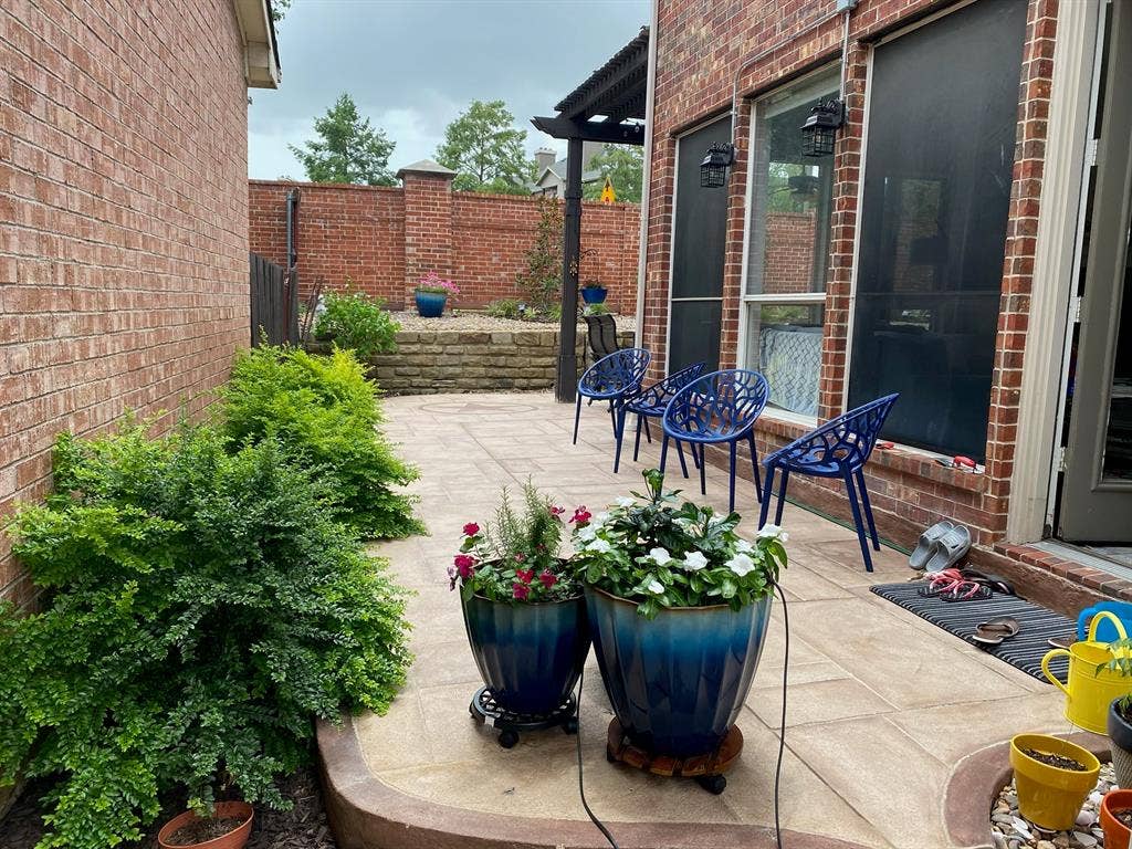 2917 Waterford Drive, Irving, TX 75063 Paved patio area, brick exterior, built-in wall sconces, terraced landscaping, and mature shrubbery