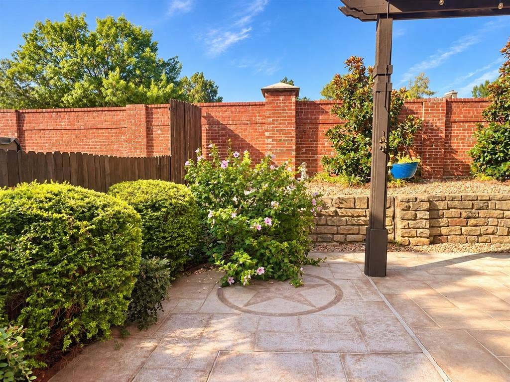2917 Waterford Drive, Irving, TX 75063 Paved patio featuring an inlaid star design, a dark wood-finish pergola, and mature landscaping