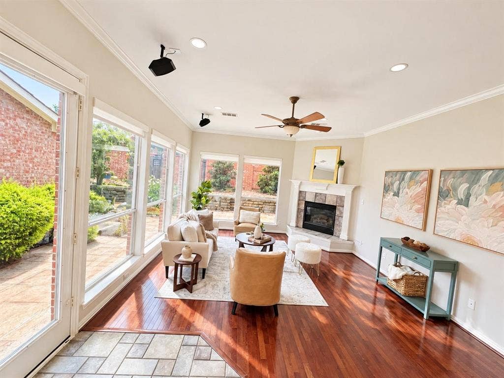 2917 Waterford Drive, Irving, TX 75063 Rich wood-finish flooring, stone-surround fireplace, ceiling fan, and extensive window system overlooking an exterior patio