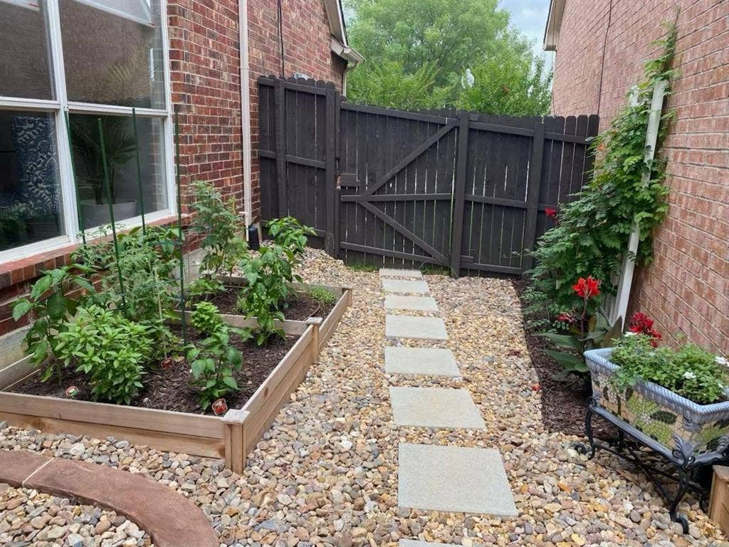 2917 Waterford Drive, Irving, TX 75063 Brick exterior with garden beds, a gravel path, stepping stones, and a dark wood privacy fence