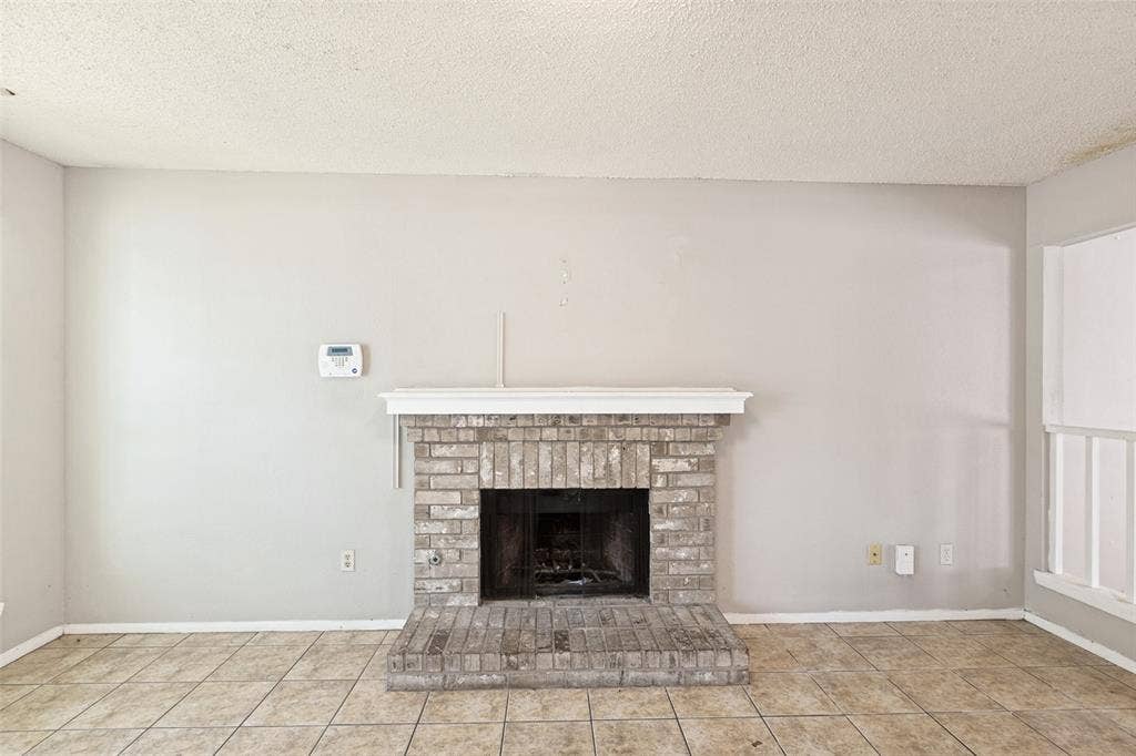12206 Tyson Cove, #A, Austin, TX 78758 Brick fireplace with a white mantel, tile flooring, and light-colored wall paint