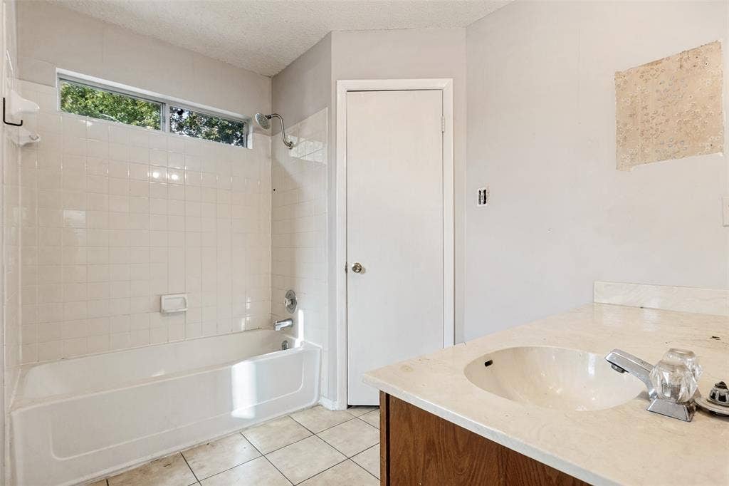 12206 Tyson Cove, #A, Austin, TX 78758 Bathroom featuring a white bathtub with subway tile surround, tiled flooring, wood-finish vanity with an integrated sink, and an upper transom window