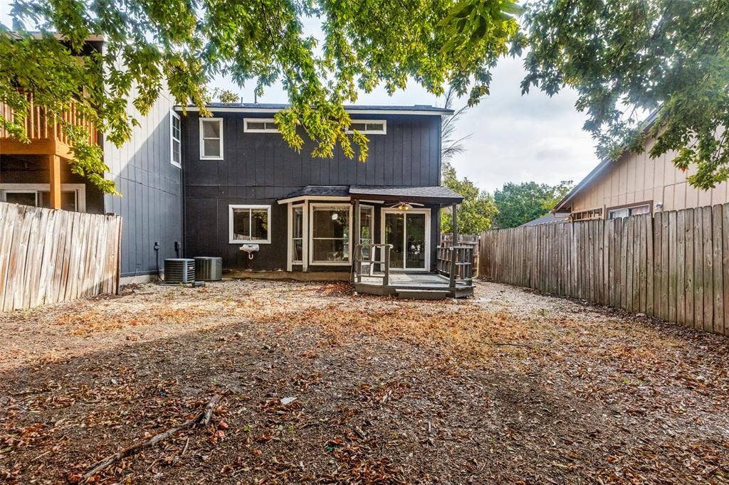12206 Tyson Cove, #A, Austin, TX 78758 Rear exterior with a dark-painted facade, multiple windows, and a ground-level deck featuring sliding glass doors